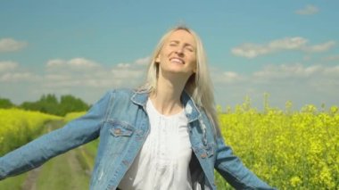 Beyaz saçlı güzel bir kadın tarlada yürüyor, kameraya bakıyor, etrafında dönüyor.