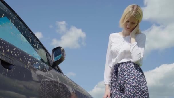 Bílá žena se dívá v zoufalství na její auto uvízl v bahně na venkově ve vesnici. — Stock video