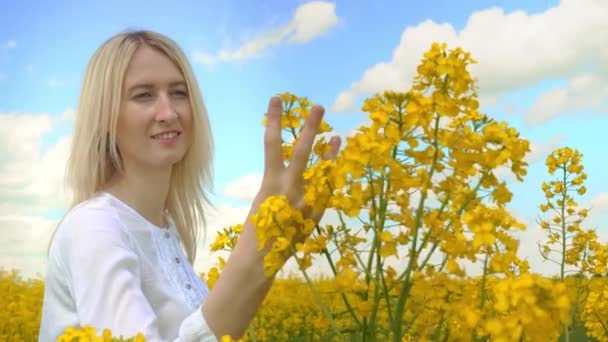 A pretty, sweet, blonde woman in rapeseed flowers. — Stock Video