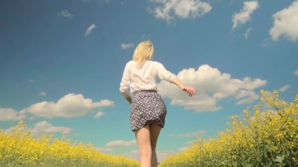 Girl runs merrily through rapeseed field. concept of child's dream of farming. — Stock Video