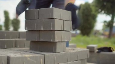 Bir işçi iş yerine tuğla yığını ya da kaldırım döşemesi serer.