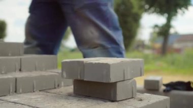 Bir işçi iş yerine tuğla yığını ya da kaldırım döşemesi serer.