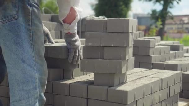 En arbetare lägger en stapel av tegel eller gatsten på arbetsplatsen — Stockvideo