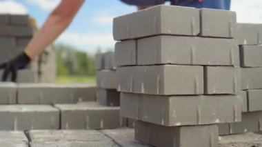 Bir işçi iş yerine tuğla yığını ya da kaldırım döşemesi serer.
