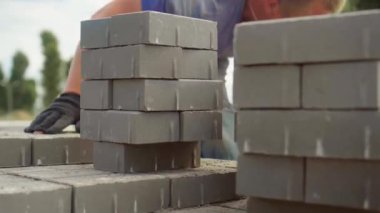 Bir işçi iş yerine tuğla yığını ya da kaldırım döşemesi serer.