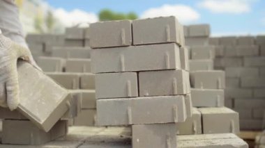 Bir işçi iş yerine tuğla yığını ya da kaldırım döşemesi serer.