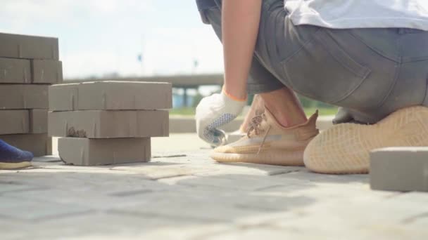 一个受雇的工人在一个炎热、阳光灿烂的日子里铺瓷砖.公园或城市的景观美化. — 图库视频影像
