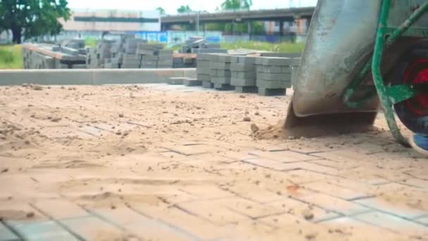 La main d'une femme balaie le sable sur la surface grise des dalles de béton avec un balai — Video