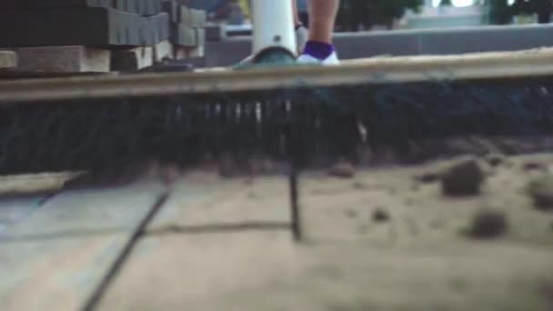 A woman's hand sweeps sand on the gray surface of concrete slabs with a broom — Stock Video