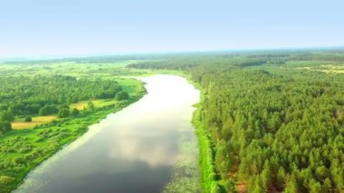 Helikopterin kamerası yeşil çimlerin ve ormanın arka planına karşı nehri çekiyor.