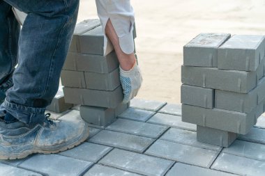 Çalışan adam bir sürü beton tuğla alıyor ve onları doğru yere taşımak istiyor.