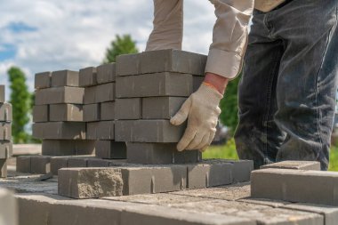 Çalışan adam bir sürü beton tuğla alıyor ve onları doğru yere taşımak istiyor.