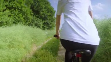 Kırsal kesimde bir yolda bisiklet süren bir kız. Mutlu ve gülümsüyor..