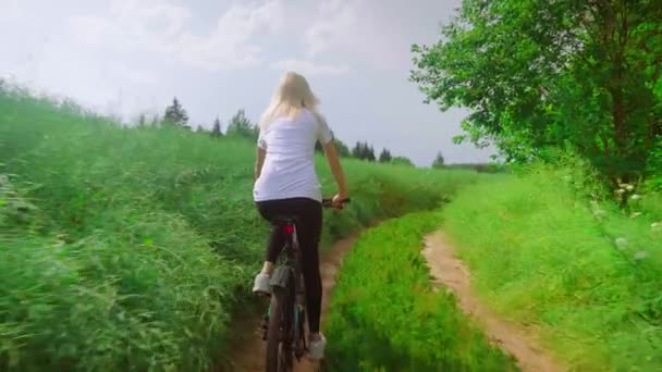 Une fille fait du vélo sur une route de campagne. Elle est heureuse et souriante. — Video