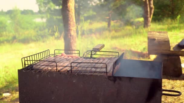 Cocinar las salchichas en una parrilla de hierro fundido al aire libre de cerca. Pitknik.. — Vídeos de Stock