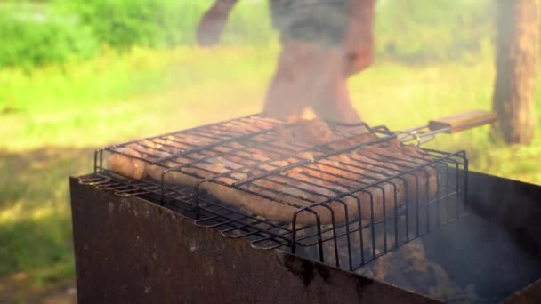 Μαγείρεμα λουκάνικων σε ψησταριά από χυτοσίδηρο σε ανοιχτό κοντινό πλάνο. Πίτναϊκ. — Αρχείο Βίντεο