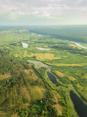 Nehirde insansız hava aracı olan güzel bir yaz manzarası. Sel çayırları, tarlalar, ormanlar. Dikey fotoğraf