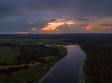 Güzel, büyüleyici bir gün batımı, gölün üzerinde bulutlar, yaz akşamında bir nehir, bir dronun manzarası.
