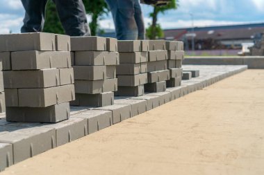 İnsanın ayakları yerde çok sayıda beton tuğlaların yanında duruyor. Asfalt döşeme kavramı