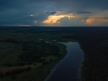 Güzel, büyüleyici bir gün batımının drone görüntüsü. Gölün üzerinde bulutlar, yaz akşamında bir nehir.