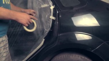 Arabanın ve diğer vücut elemanlarının deliklerini boya bandıyla kapatan bir ressam.,