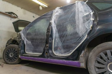 Bir araba ve diğer vücut elemanlarının deliklerini boya bandıyla kapatan bir boyacı bir araba tamirhanesinde boyayla doldurmamak için. Bir filmle yapıştırılıyor.