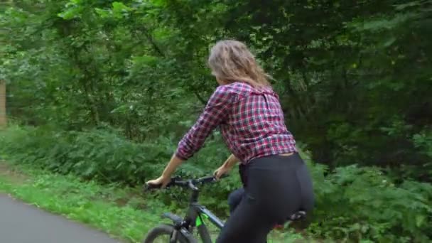 Uma jovem mulher anda de bicicleta pela floresta. Ela gosta de floresta limpa ar fresco — Vídeo de Stock