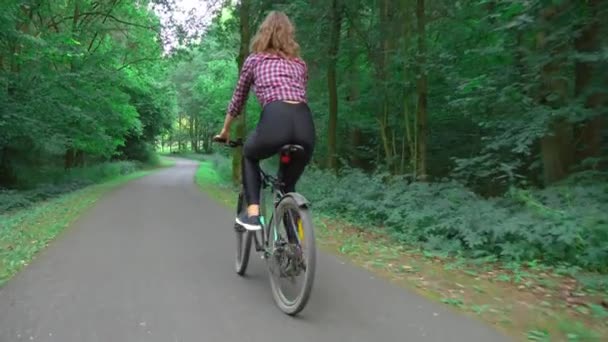 Atleta fêmea passeios de bicicleta ao longo da estrada florestal e goza de ar e a vista. — Vídeo de Stock