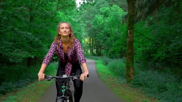 Egy fiatal nő biciklizik az erdőben. Szereti a friss levegőt.