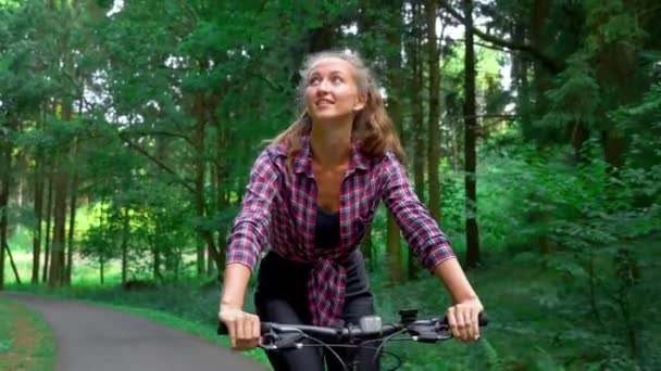 Жінка-спортсмен їде на велосипеді уздовж лісової дороги і насолоджується повітрям і видом . — стокове відео
