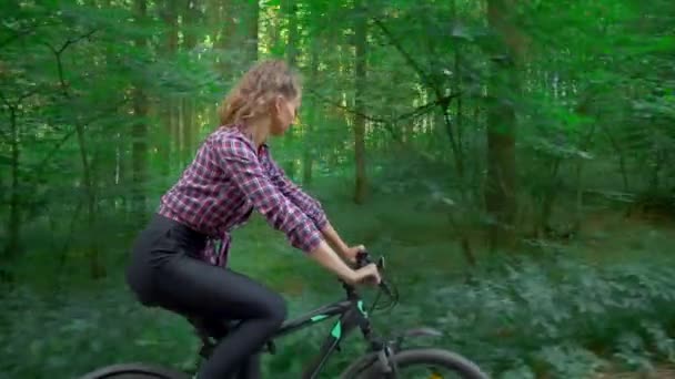 Athlète féminine fait du vélo le long de la route forestière et profite de l'air et de la vue. — Video