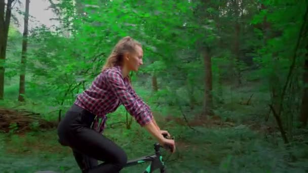 นักกีฬาหญิงขี่จักรยานไปตามถนนป่าและเพลิดเพลินกับอากาศและวิว . — วีดีโอสต็อก