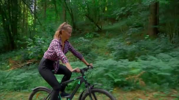 Uma jovem mulher anda de bicicleta pela floresta. Ela gosta de floresta limpa ar fresco — Vídeo de Stock