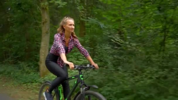 Atleta fêmea passeios de bicicleta ao longo da estrada florestal e goza de ar e a vista. — Vídeo de Stock