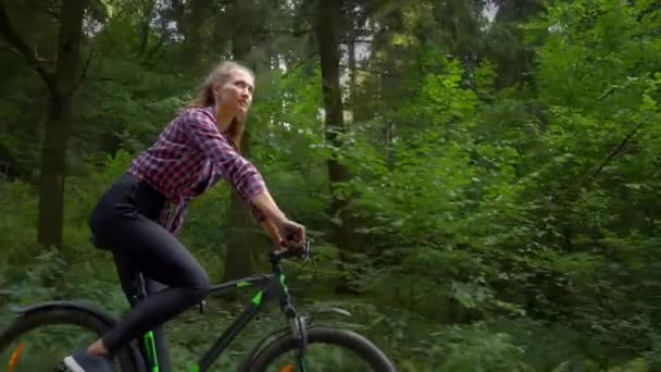 Eine junge Frau fährt mit dem Fahrrad durch den Wald. Sie genießt saubere Waldluft — Stockvideo