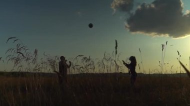 Üç genç enerjik insan sahada gün batımında voleybol oynuyorlar..