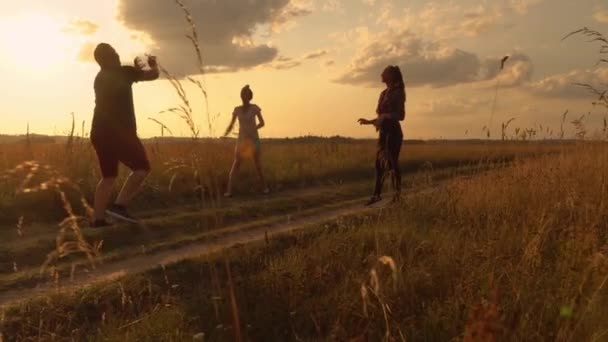 En grupp ungdomar spelar volleyboll på planen vid solnedgången. — Stockvideo