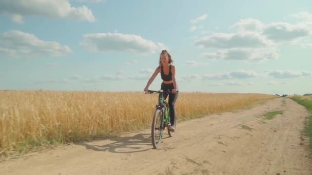 Sportive belle brune mangeant sur le terrain en été sur un vélo de sport. — Video