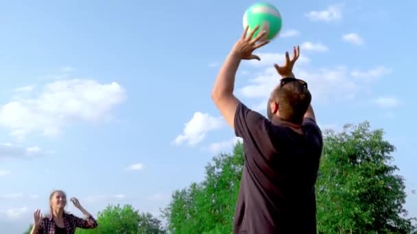 Skupina mladých lidí hraje volejbal na hřišti při západu slunce. zpomalený pohyb, — Stock video