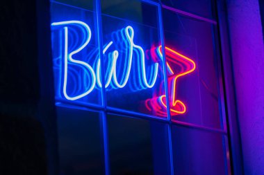 Beautiful blue neon bar sign with a red neon glass on the window. Advertising neon sign glows in the dark