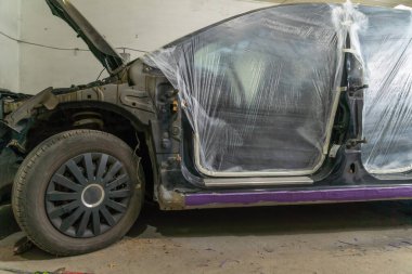 Bir araba ve diğer vücut elemanlarının deliklerini boya bandıyla kapatan bir boyacı bir araba tamirhanesinde boyayla doldurmamak için. Bir filmle yapıştırılıyor.