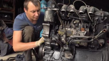 Otomatik tamirci içten yanmalı motoru kontrol eder. Motor petrolle kaplı.