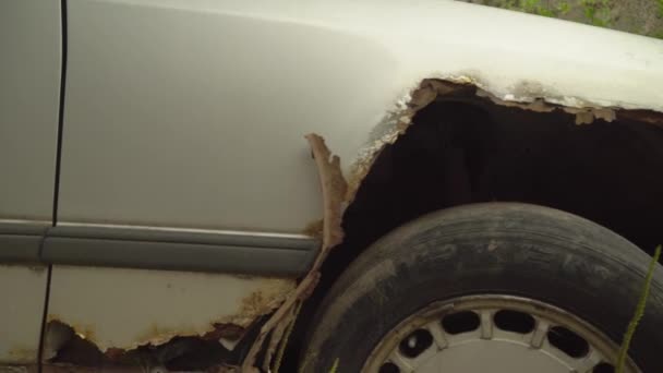 Zrezivělé opuštěné auto na parkovišti, obklopené plotem a ostnatým drátem. — Stock video