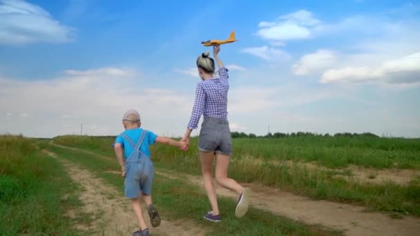 Madre e hijo juegan al aire libre, lanzan un avión de juguete. Bebé feliz. — Vídeos de Stock