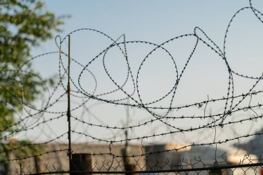 Gün batımında gökyüzünün arka planında dikenli tel var.