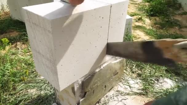 Строитель режет или режет блок пилой, чтобы сделать его размером с стену. — стоковое видео