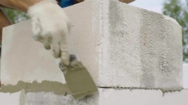 İnşaatçı, duvar yapısına spatula ile yapıştırıcı bileşimi veya çözeltisi uygular.