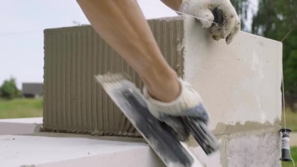 建筑商应用粘合剂组合物或带有喷头的溶液来放置下一个块. — 图库视频影像