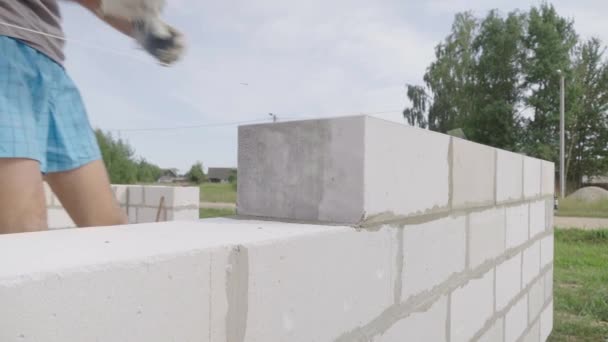 Erbauer trägt Klebstoffzusammensetzung oder Lösung mit Spachtel auf, um den nächsten Block zu setzen. — Stockvideo