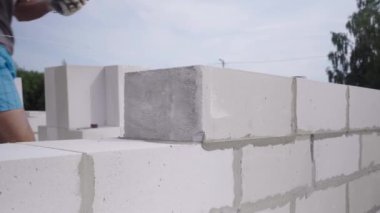 Duvarcı bir blok duvar döşeyen, açık havada macun için bir spatula ile.